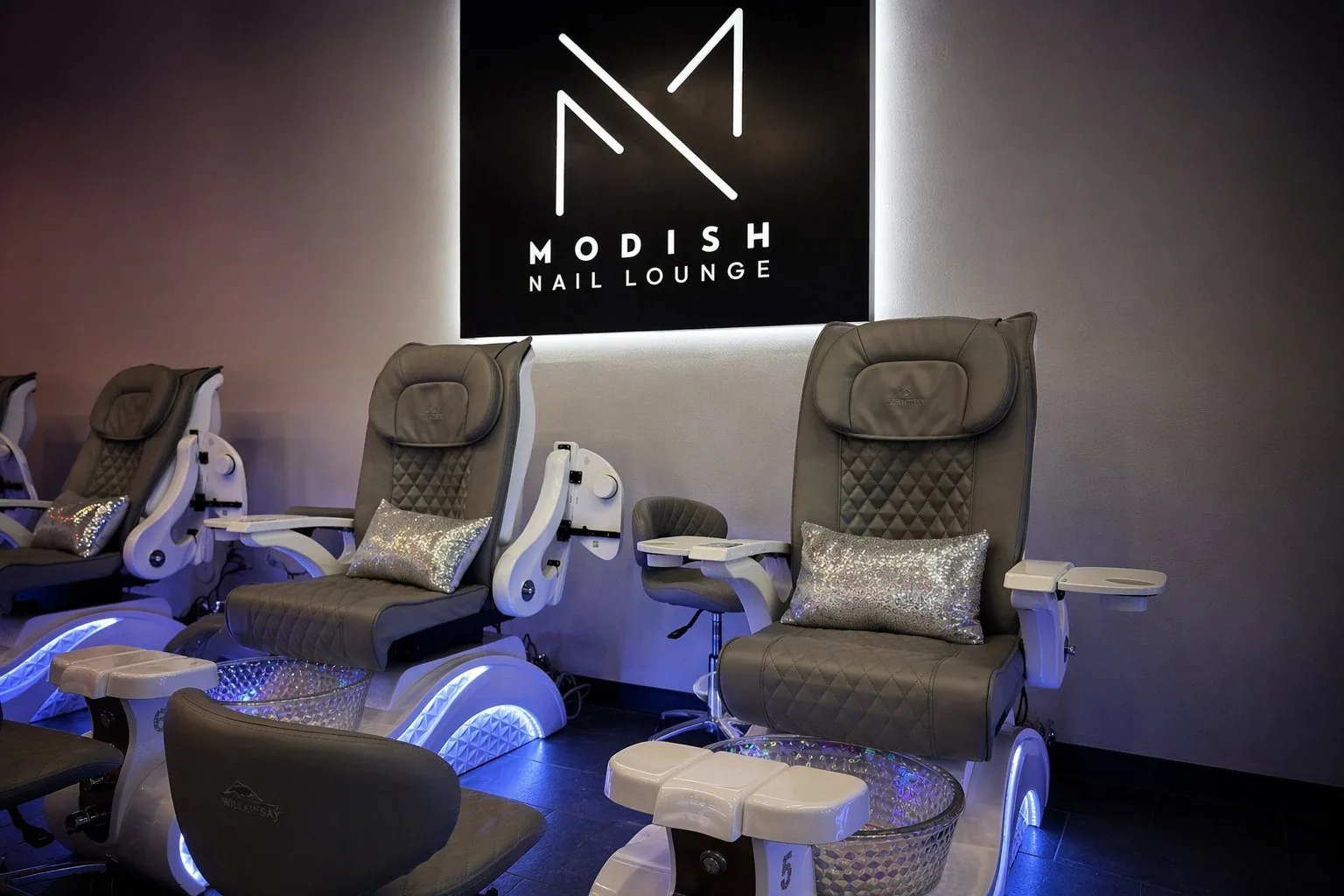 Interior of Modish Nail Lounge — luxury pedicure chairs with backlit Modish sign